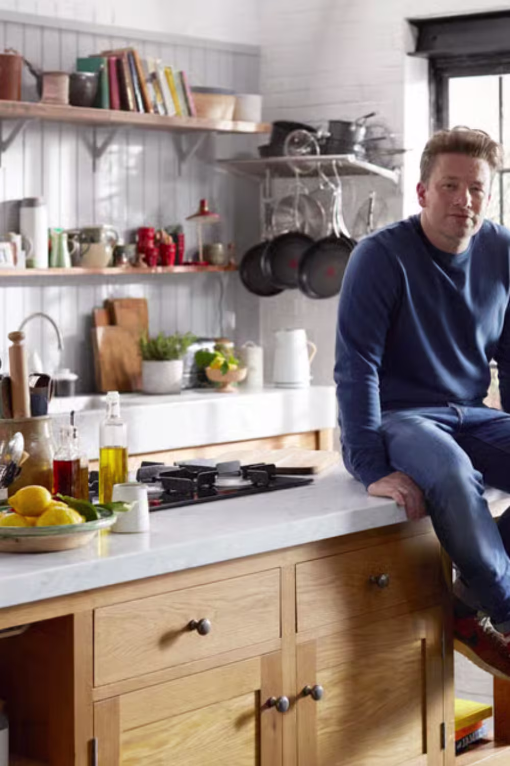 Jamie Oliver sitting on his wooden kitchen island